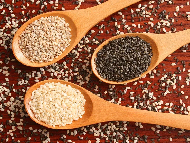 Sesame seeds (Sesamum indicum) — white, natural and black seeds in wooden spoons
